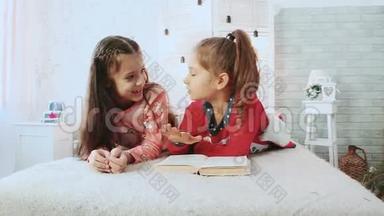 两个小朋友，穿着睡衣，他们在看书。 他们谈论和讨论这本书。